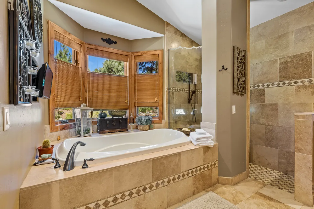 A spa-inspired bathroom with a freestanding bathtub positioned near large windows, decorative elements enhancing the space, and an overall atmosphere of serenity and luxury.