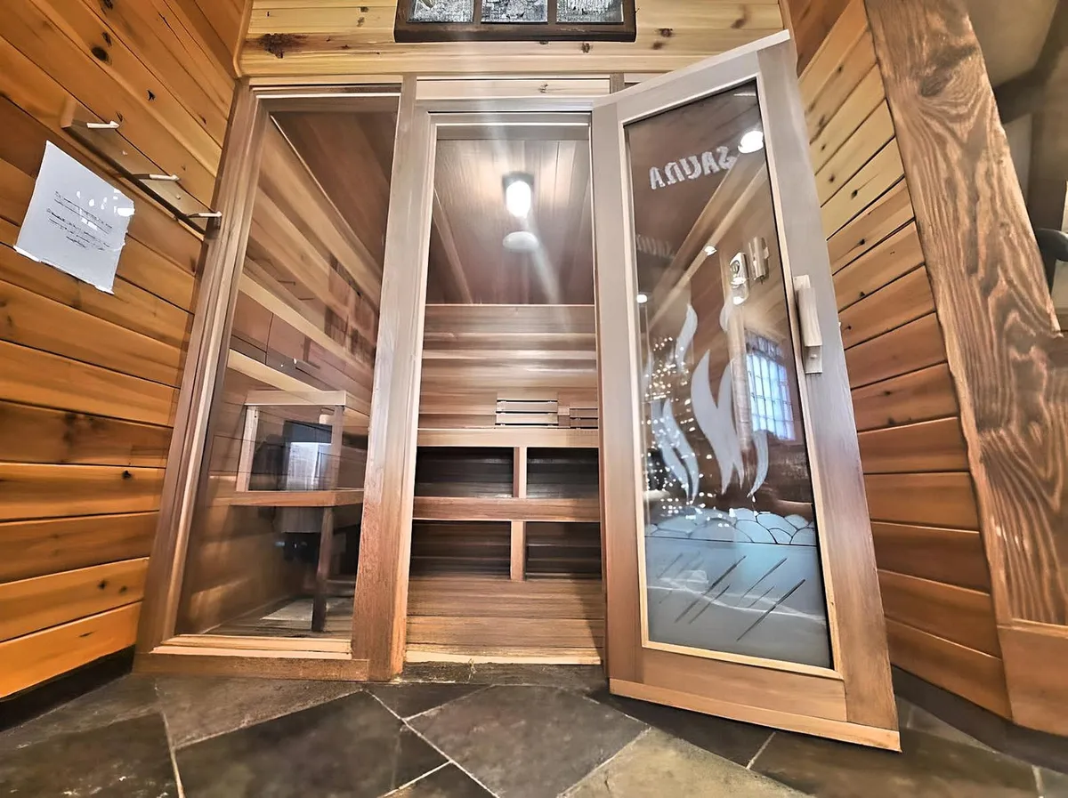 A tranquil private sauna with wooden interiors, a glass door, and soft lighting, creating an intimate space for rejuvenation and wellness routines.
